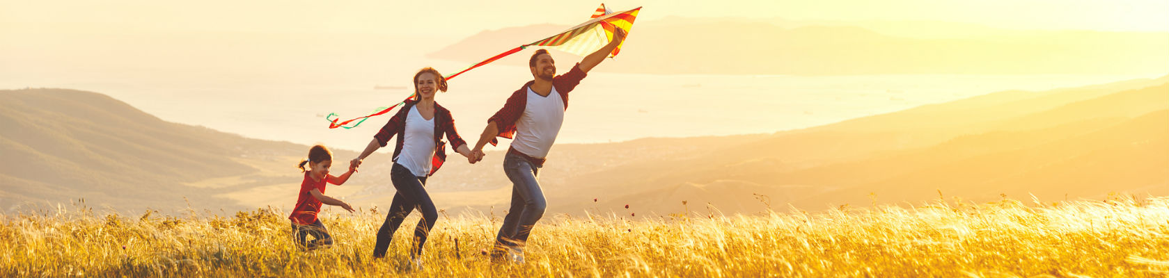 How we work - Brainstorm Health - Family flying kite in open fields with hills and ocean in background